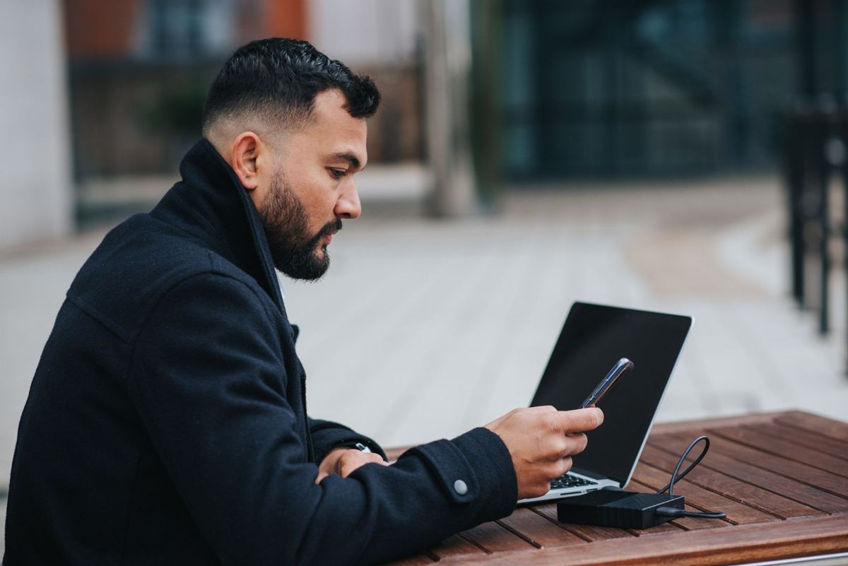 Person using a phone and a laptop